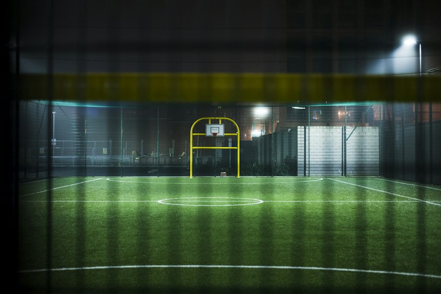 Proyectores iluminando un pequeño campo deportivo por la noche